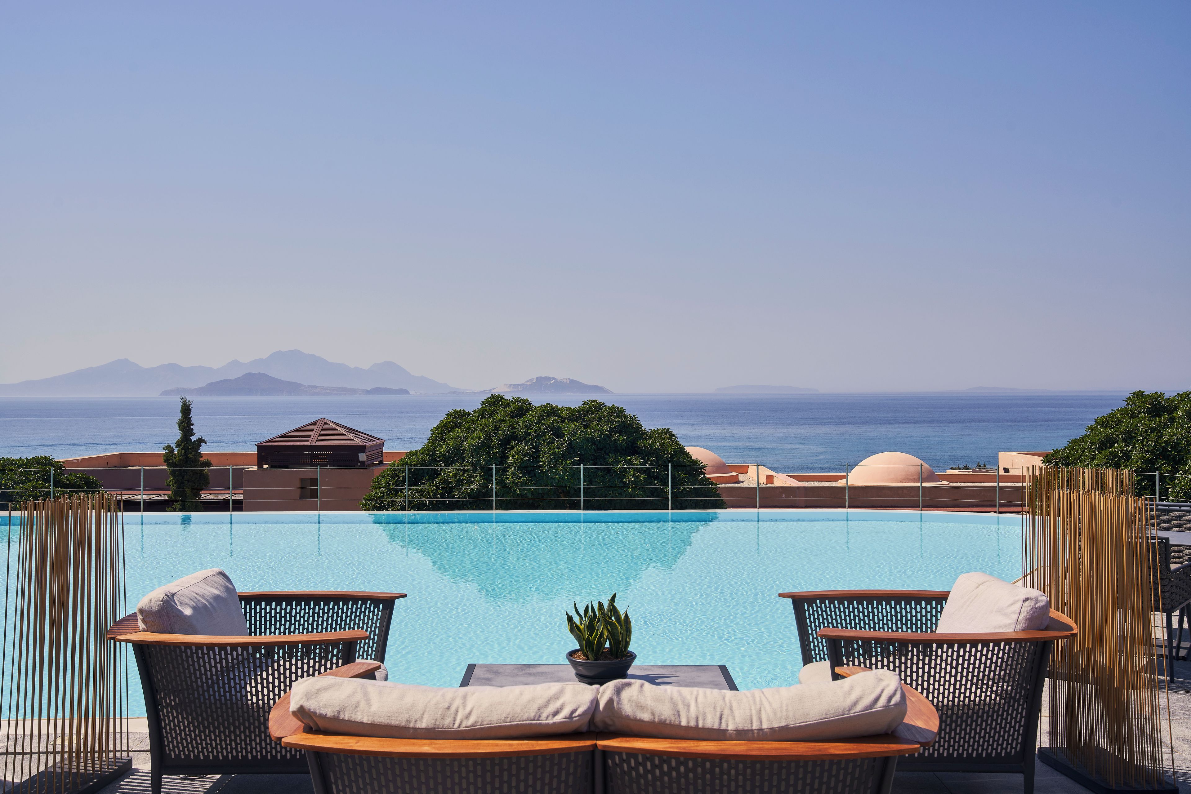 A poolside area with lounge chairs and a view of the sea.