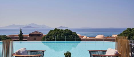 Un área junto a la piscina con sillones de descanso y vistas al mar.