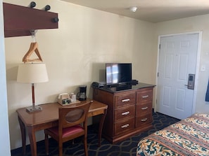 A hotel room with a wooden desk, a chair, a television on a dresser, a coffee maker, and a patterned bedspread. - Holiday Motel Oakdale (Oakdale)