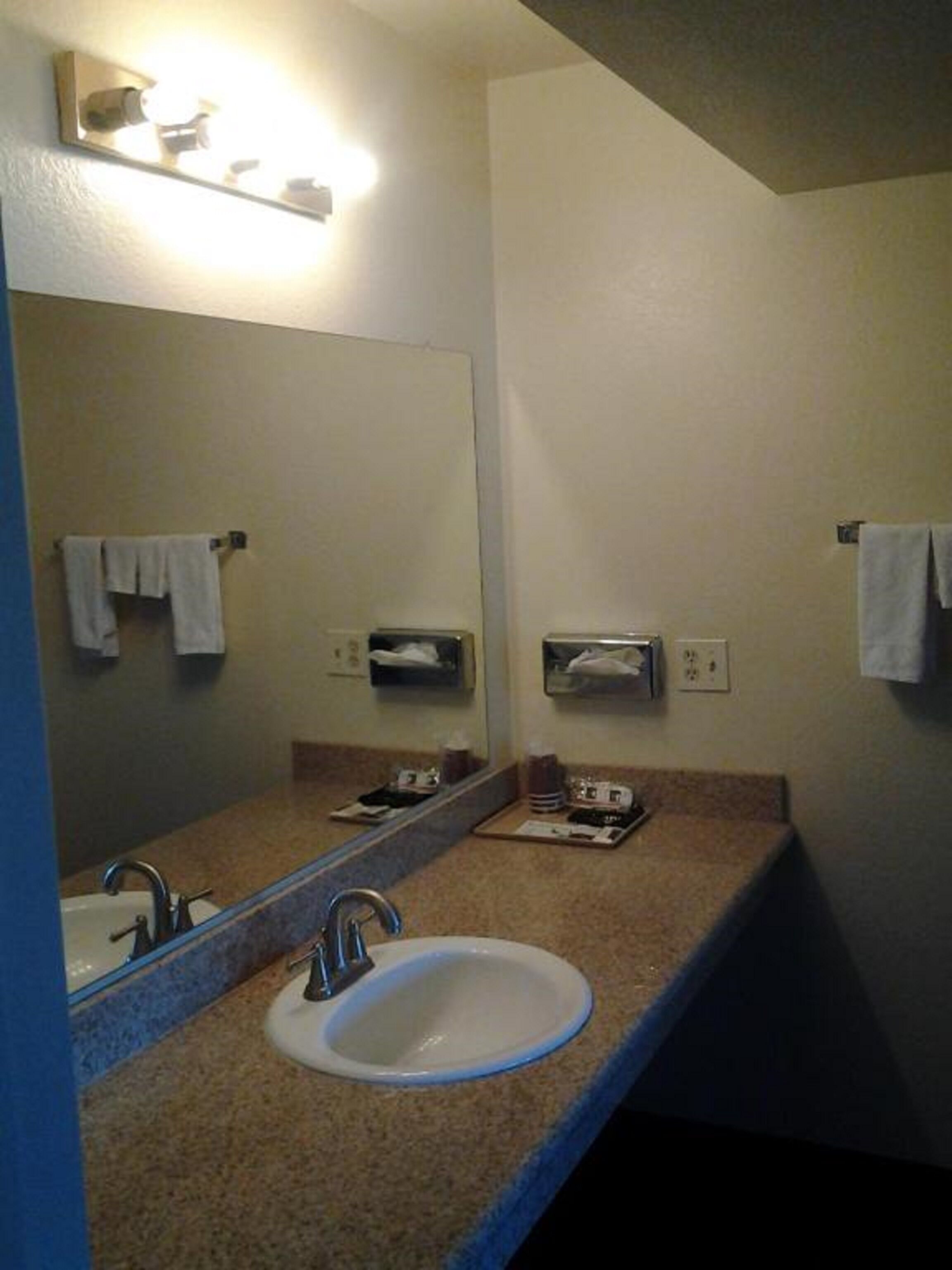 A bathroom with a sink, mirror, towel rack, and hand dryer.