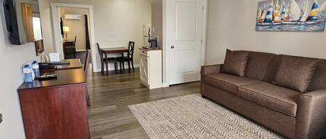 Una sala de estar con un sofá marrón, una mesa de centro de madera y una alfombra estampada.