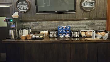 A bar area with a television, a coffee machine, and various food items.