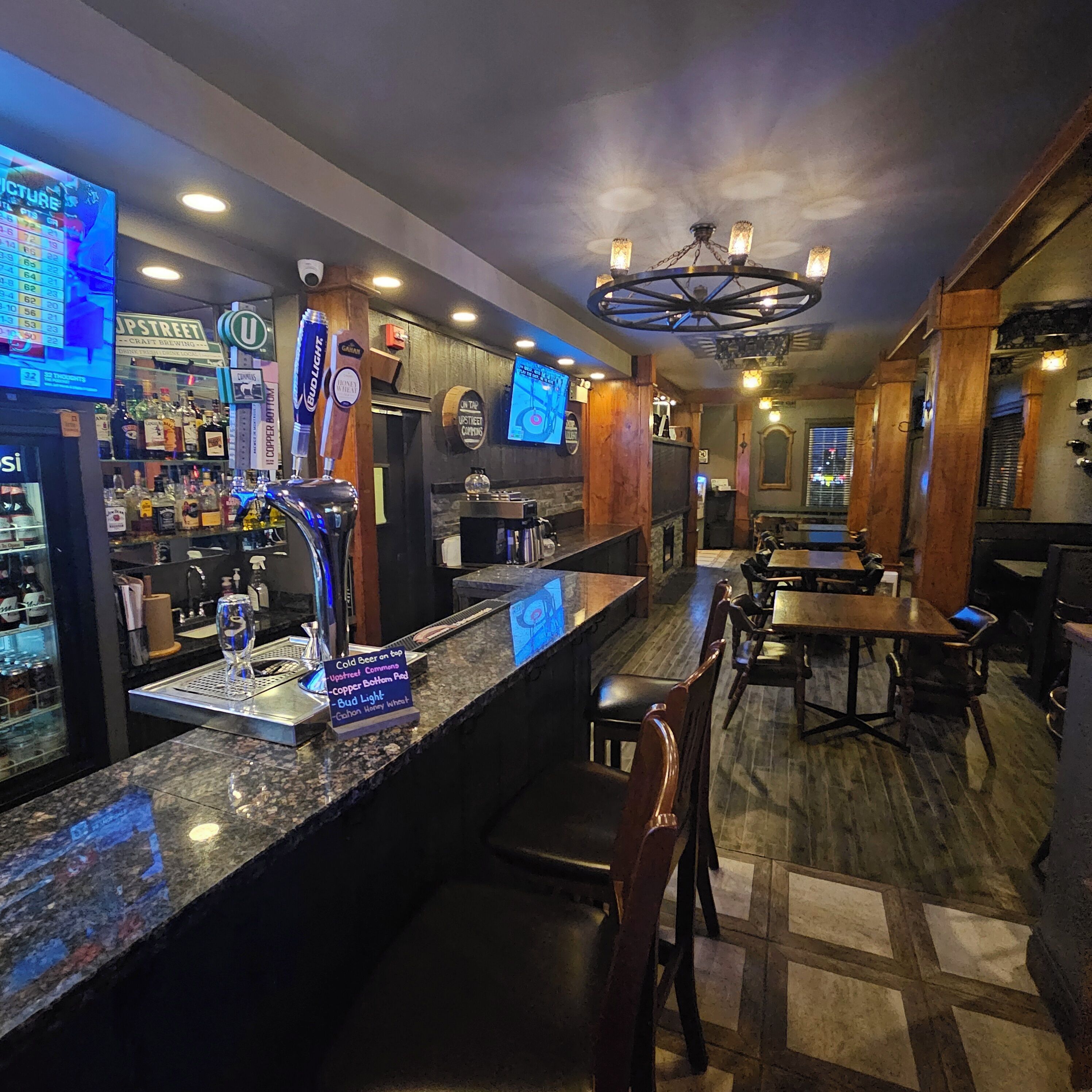 Zona de bar con mostrador, grifos de cerveza y área de estar con mesas y sillas.