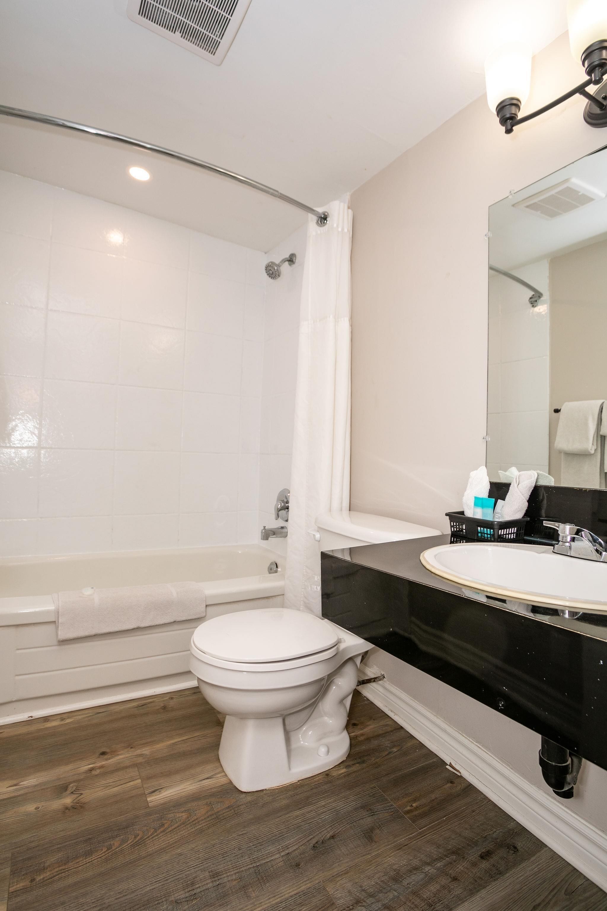 A bathroom with a bathtub, toilet, and sink.