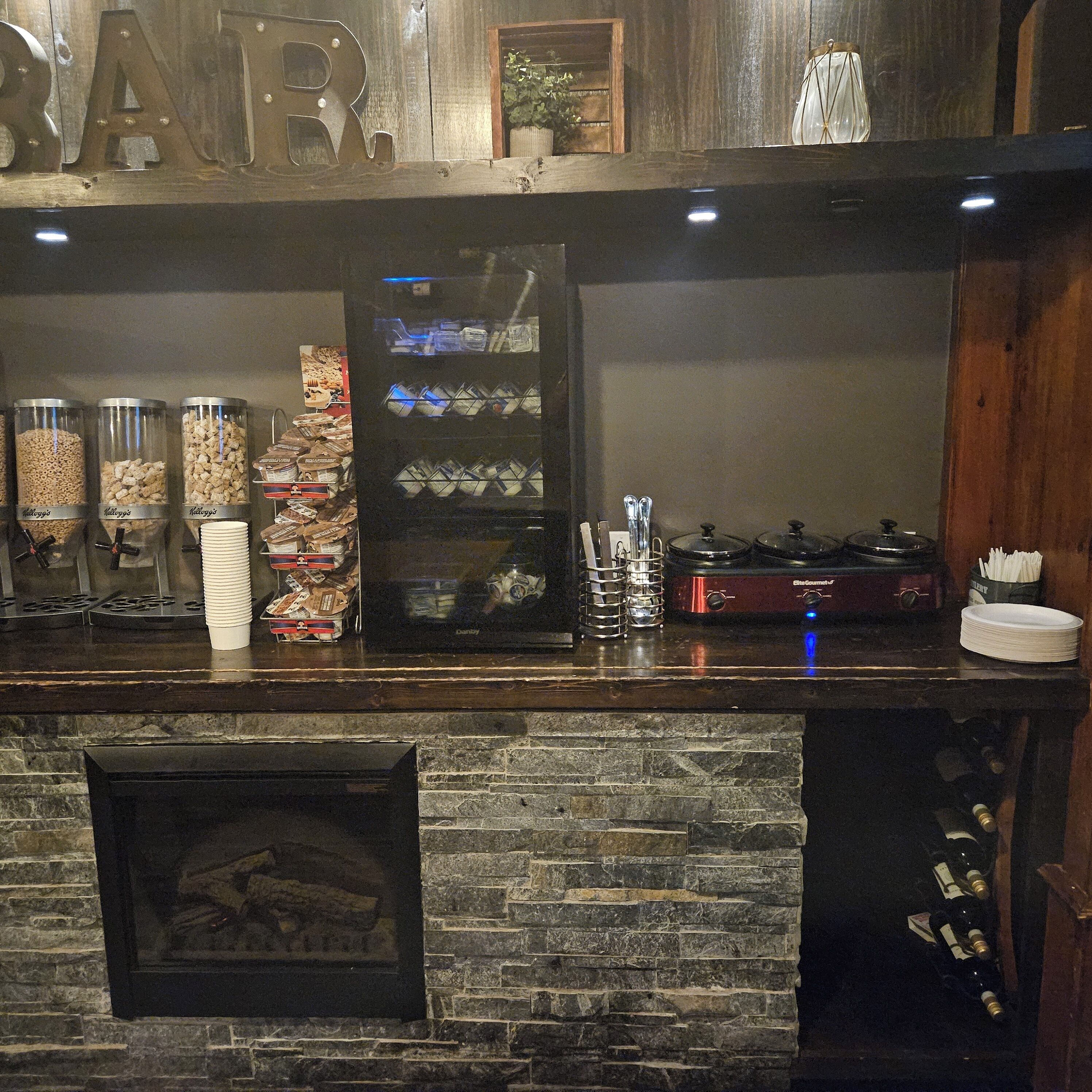 Una zona de bar con chimenea de piedra, máquinas expendedoras de aperitivos y una cafetera.