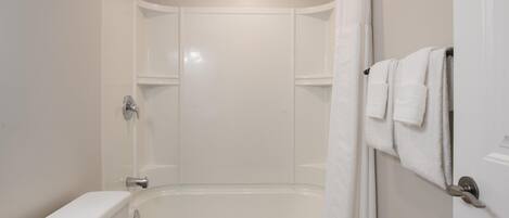 Une salle de bain moderne équipée d’une baignoire, de toilettes et d’un espace douche.