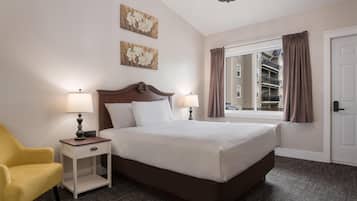 Ein Hotelzimmer mit einem großen Bett, zwei Nachttischlampen, einem Nachttisch, einem gelben Sessel und einem Fenster mit Vorhängen.