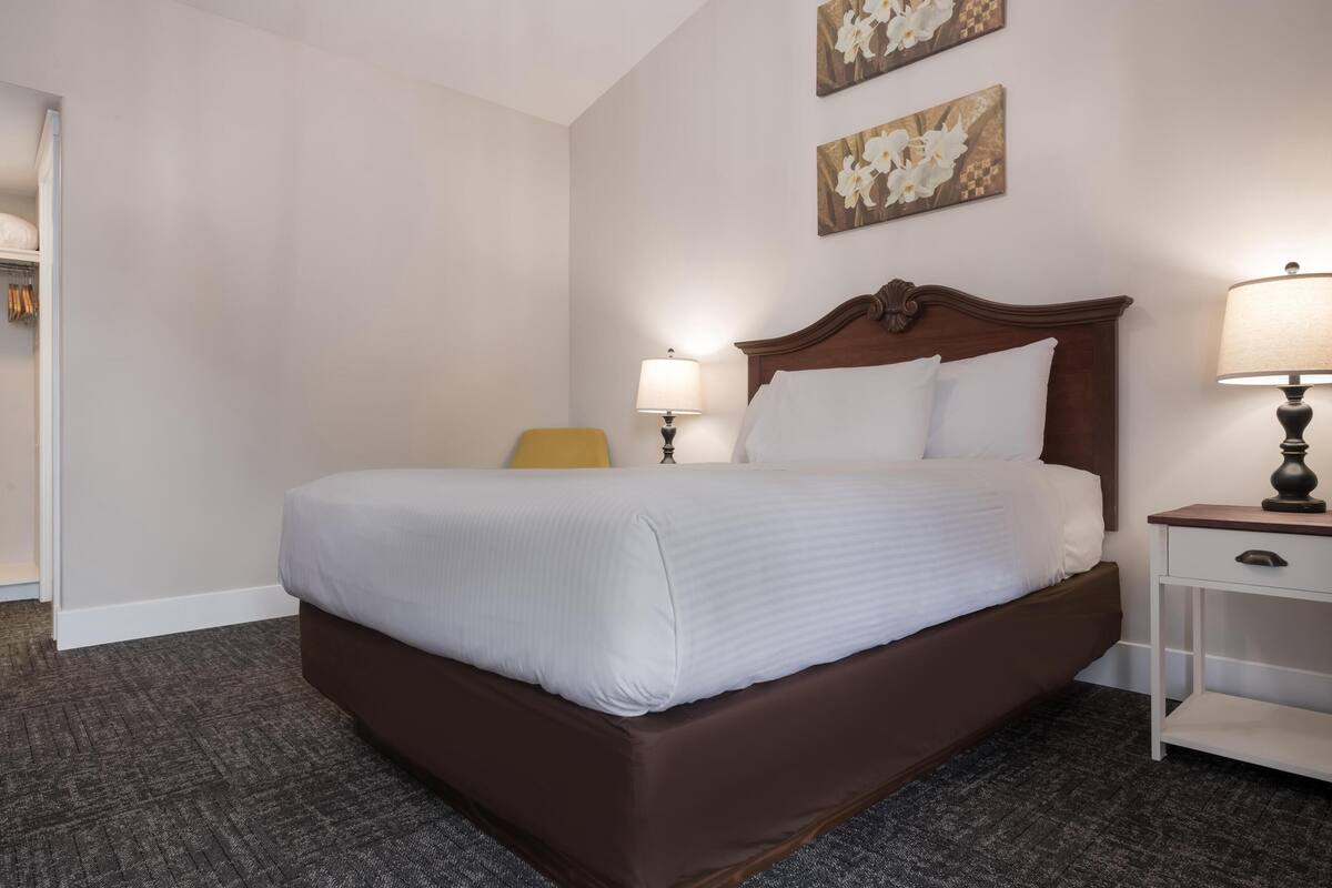 A hotel room with a large bed, a bedside table with a lamp, and a chair.