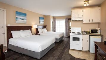 Een hotelkamer met twee bedden, een kitchenette, een magnetron en een fornuis.