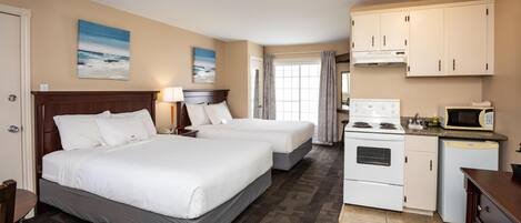 Una habitación de hotel con dos camas, un kitchenette, un microondas y una estufa.