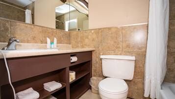Une salle de bain équipée de toilettes, d’un lavabo et d’étagères où sont rangées les serviettes.