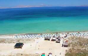 Rannalla, aurinkotuoleja, aurinkovarjoja, rantapyyhkeitä