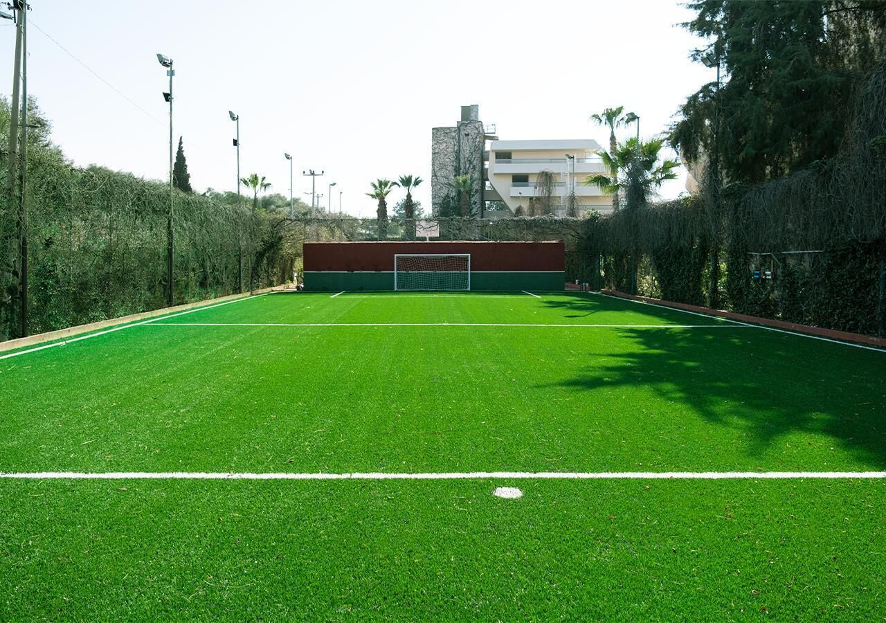 A soccer field with goalposts, surrounded by trees and a building in the background.