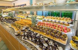 En buffet med et udvalg af mad, herunder frugt, kager og desserter.