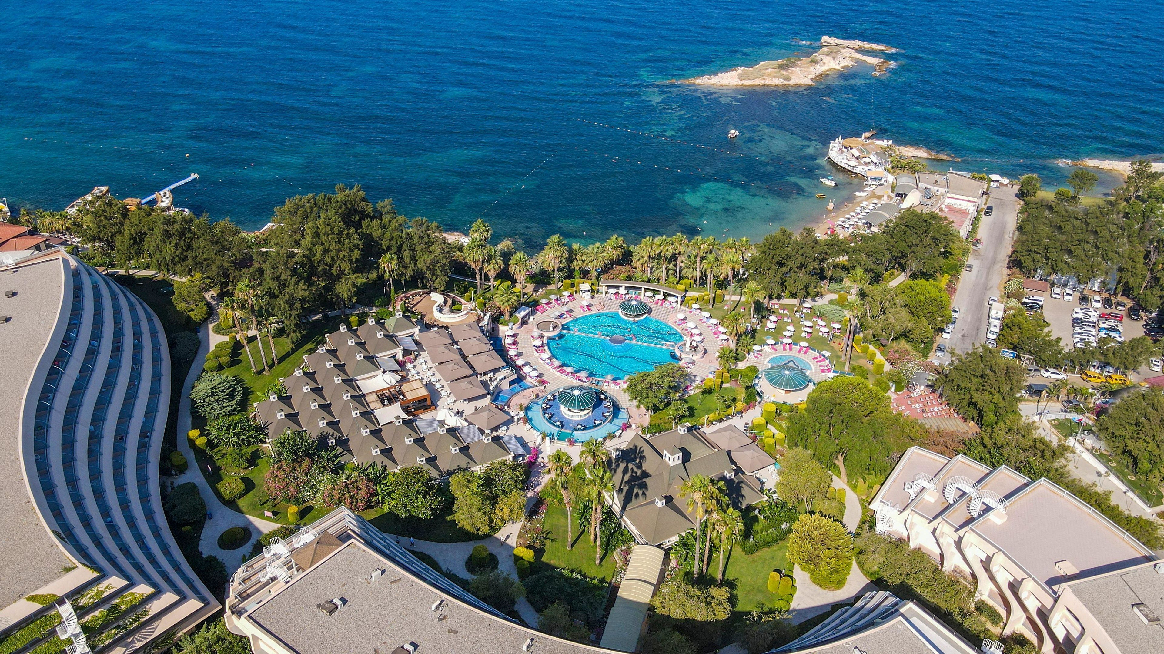 Vista aérea de un resort con varias piscinas, un puerto deportivo y un amplio estacionamiento.
