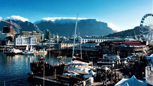 A marina with boats docked, a Ferris wheel, and buildings in the background. - 5 Options (Cape Town)