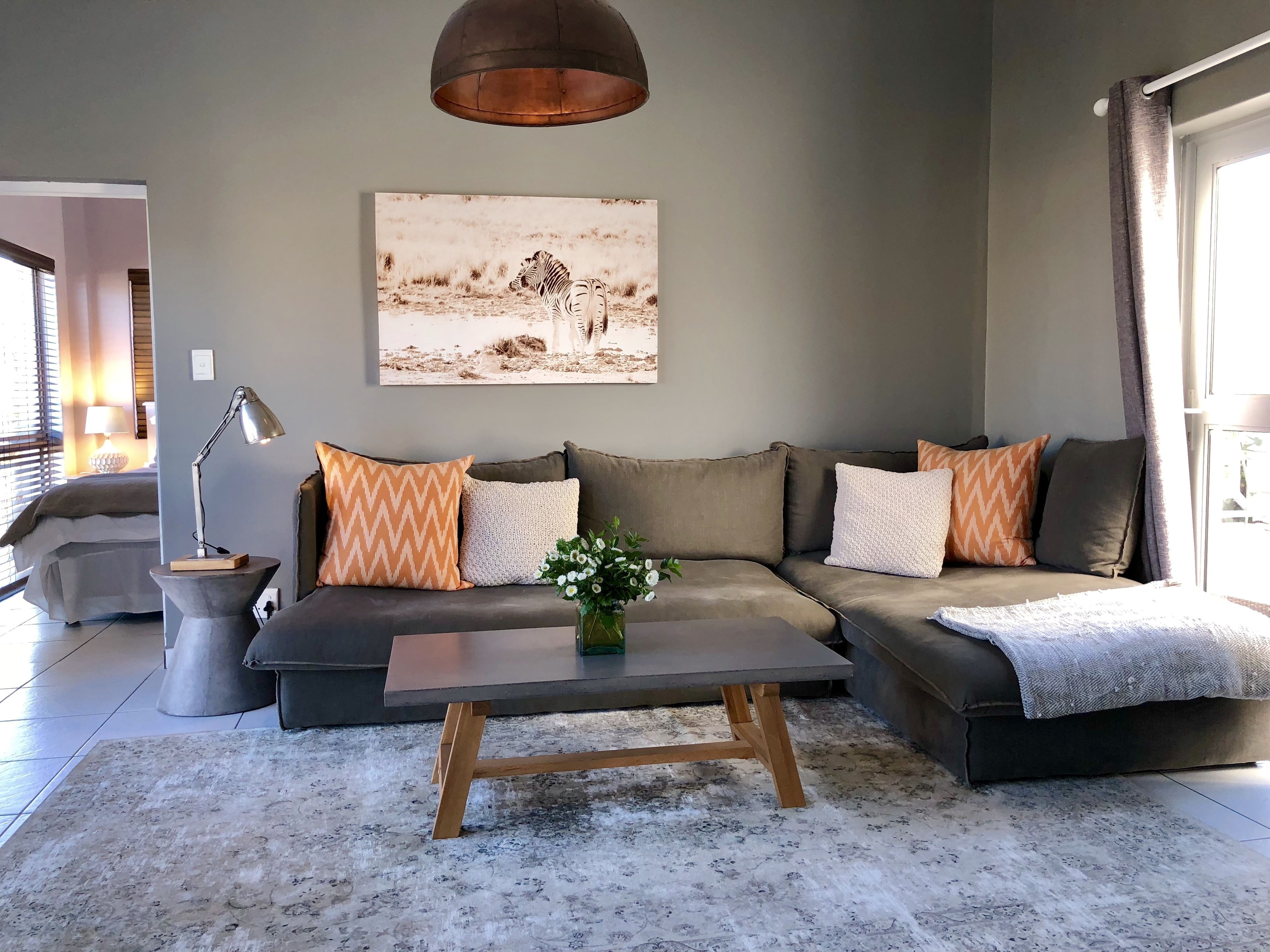 A modern living room with a sectional sofa, a coffee table, and a large painting of zebras on the wall.