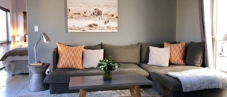 A modern living room with a sectional sofa, a coffee table, and a large painting of zebras on the wall.