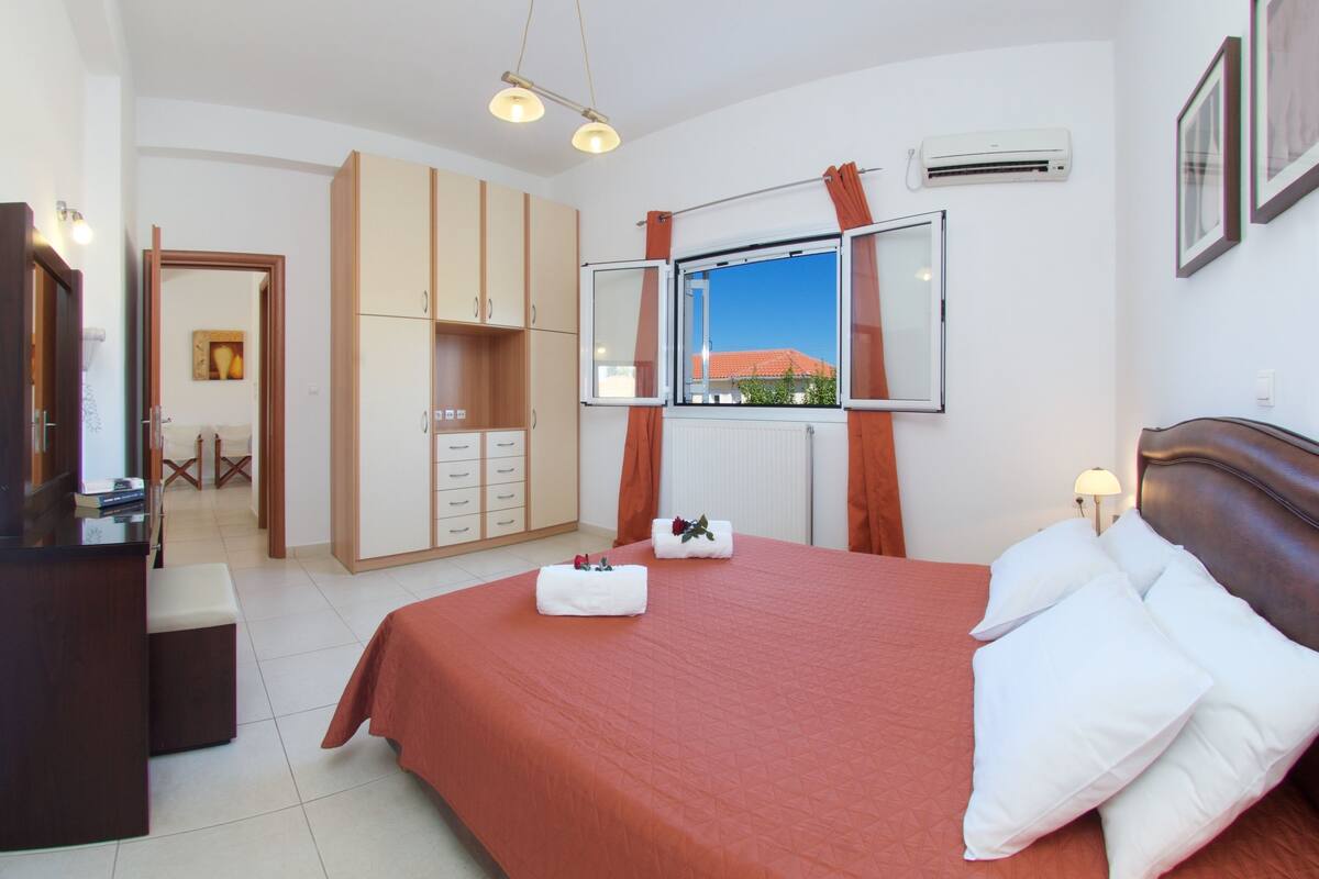 A hotel room with a large bed, a desk, a wardrobe, and a window with curtains.