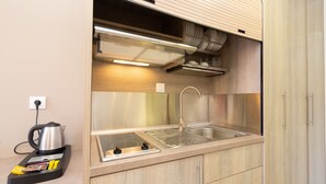A compact kitchen with a built-in stove, sink, and overhead ventilation hood. - Studios Diamanto (Kefalonia)