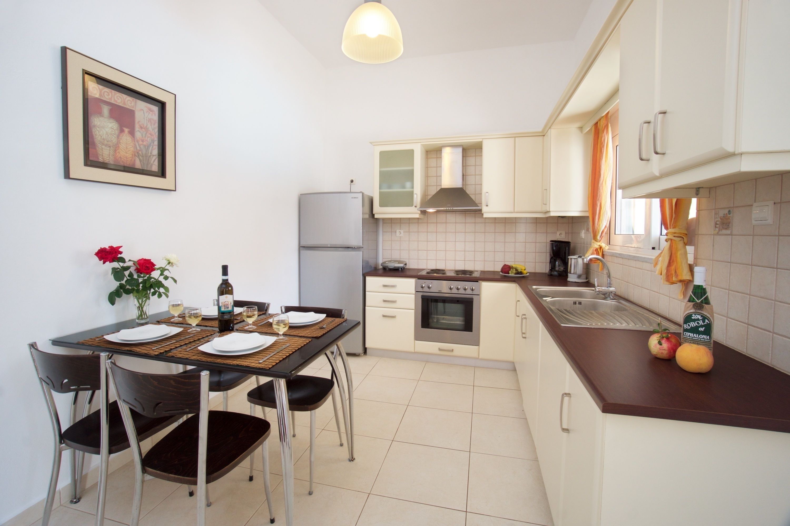 A compact kitchen with a dining table set for two, a refrigerator, oven, and a sink.