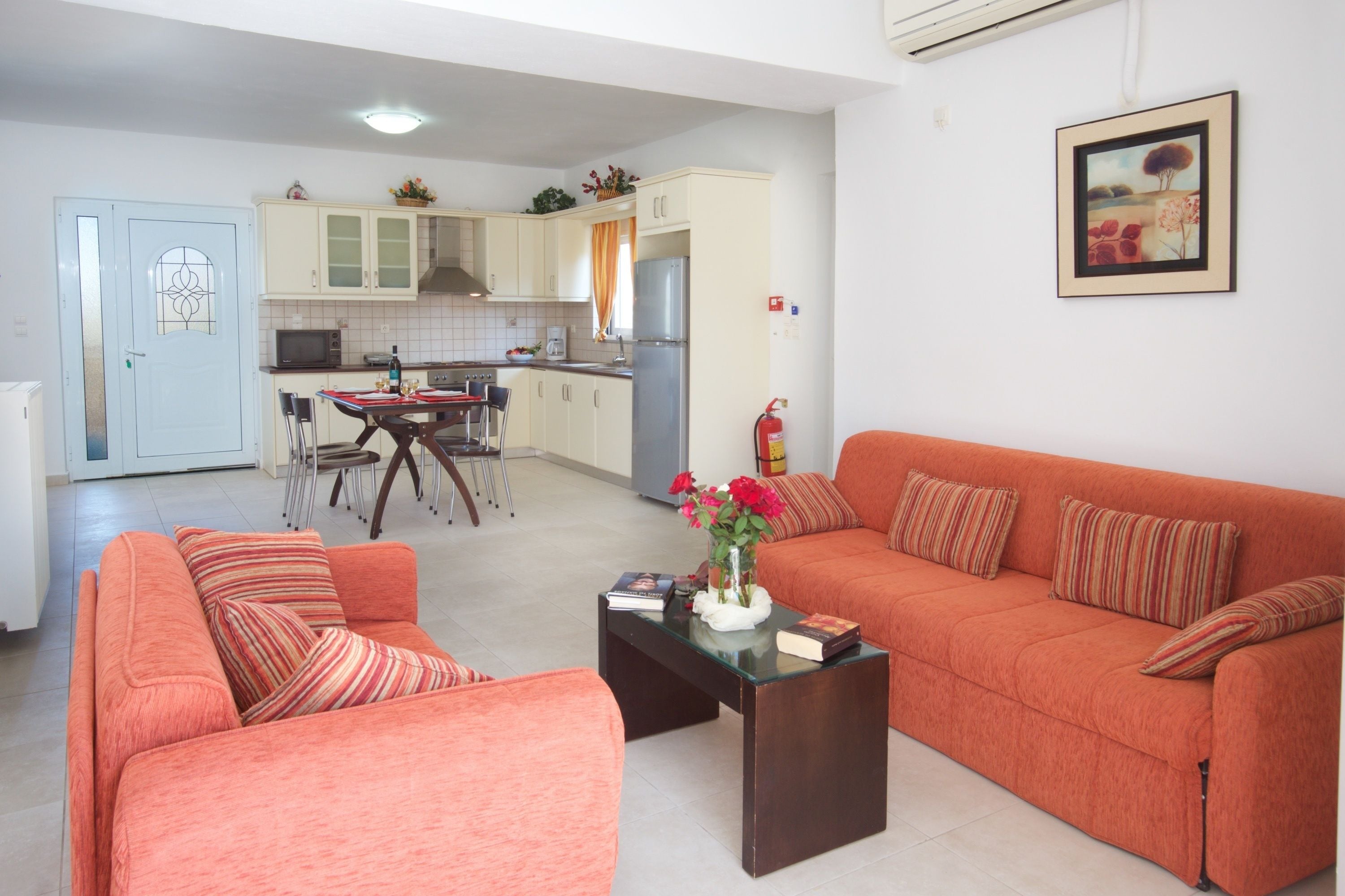 A living room with a sofa, a coffee table with a vase of flowers, and a dining area with chairs and a table.