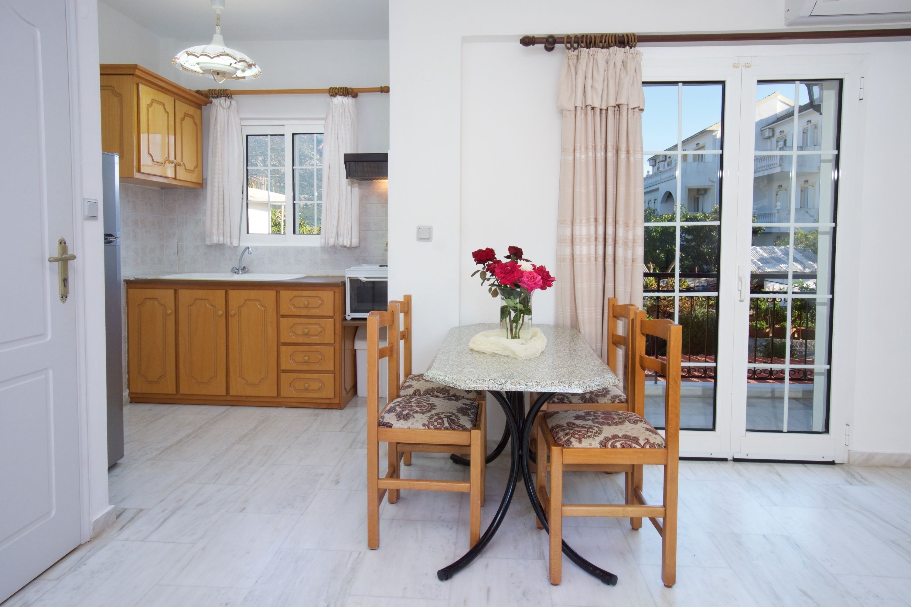 A kitchen with wooden cabinets, a dining table with chairs, and a vase with flowers.
