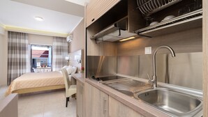 A modern hotel room with a kitchenette, a bed, a bathroom, and a view of the outside. - Studios Diamanto (Kefalonia)