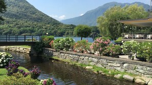 Vista al río con un muro de piedra, flores y un puente.