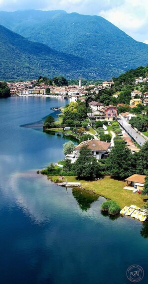 Un pueblo a orillas de un lago con una iglesia destacada, edificios residenciales y un área de embarcadero.