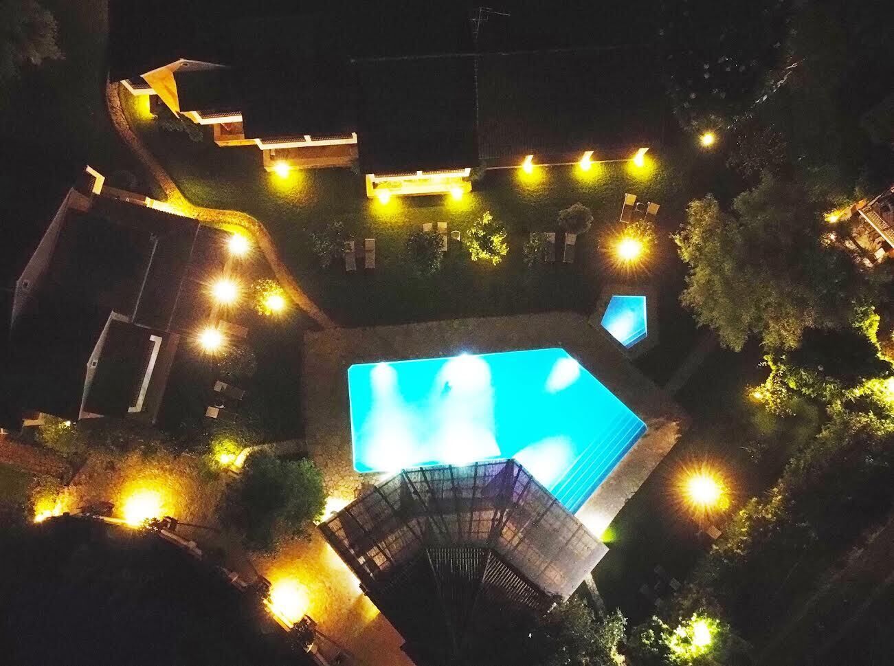 A swimming pool surrounded by a well-lit deck area with a few lounge chairs.
