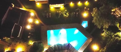 Ein Schwimmbecken, umgeben von einem gut beleuchteten Deck mit einigen Liegestühlen.