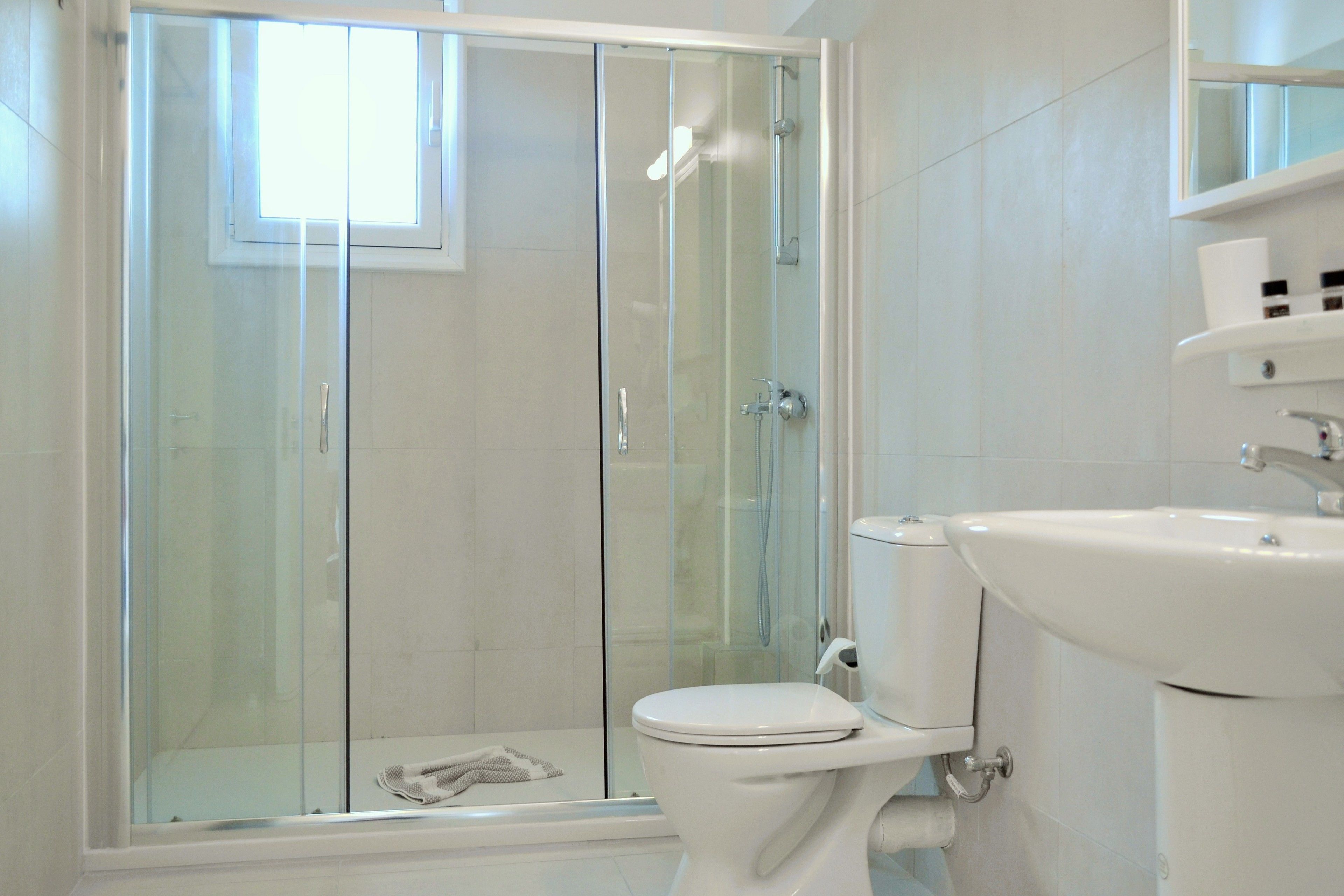 A modern bathroom with a glass-enclosed shower, a white toilet, and a sink.