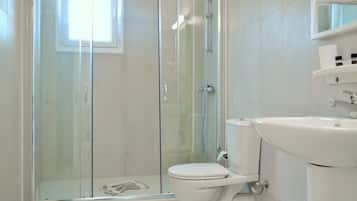 Un baño moderno con ducha envuelta en vidrio, inodoro blanco y lavamanos.