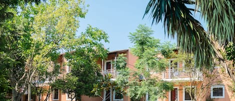 Un edificio de dos pisos con fachada roja, rodeado de árboles y un césped bien cuidado.