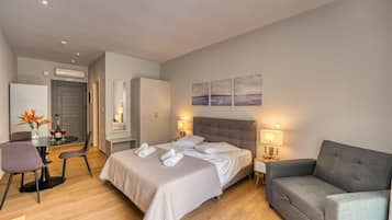 Una habitació d'hotel moderna amb un llit, un sofà, una taula de treball amb una cadira i una taula de dinar.