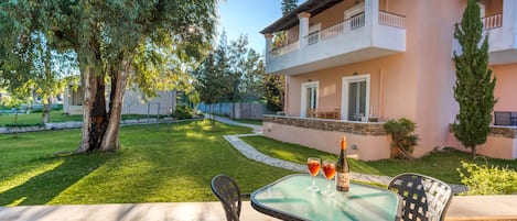 A patio with a glass table and chairs, a bottle of wine, and a glass of red wine.