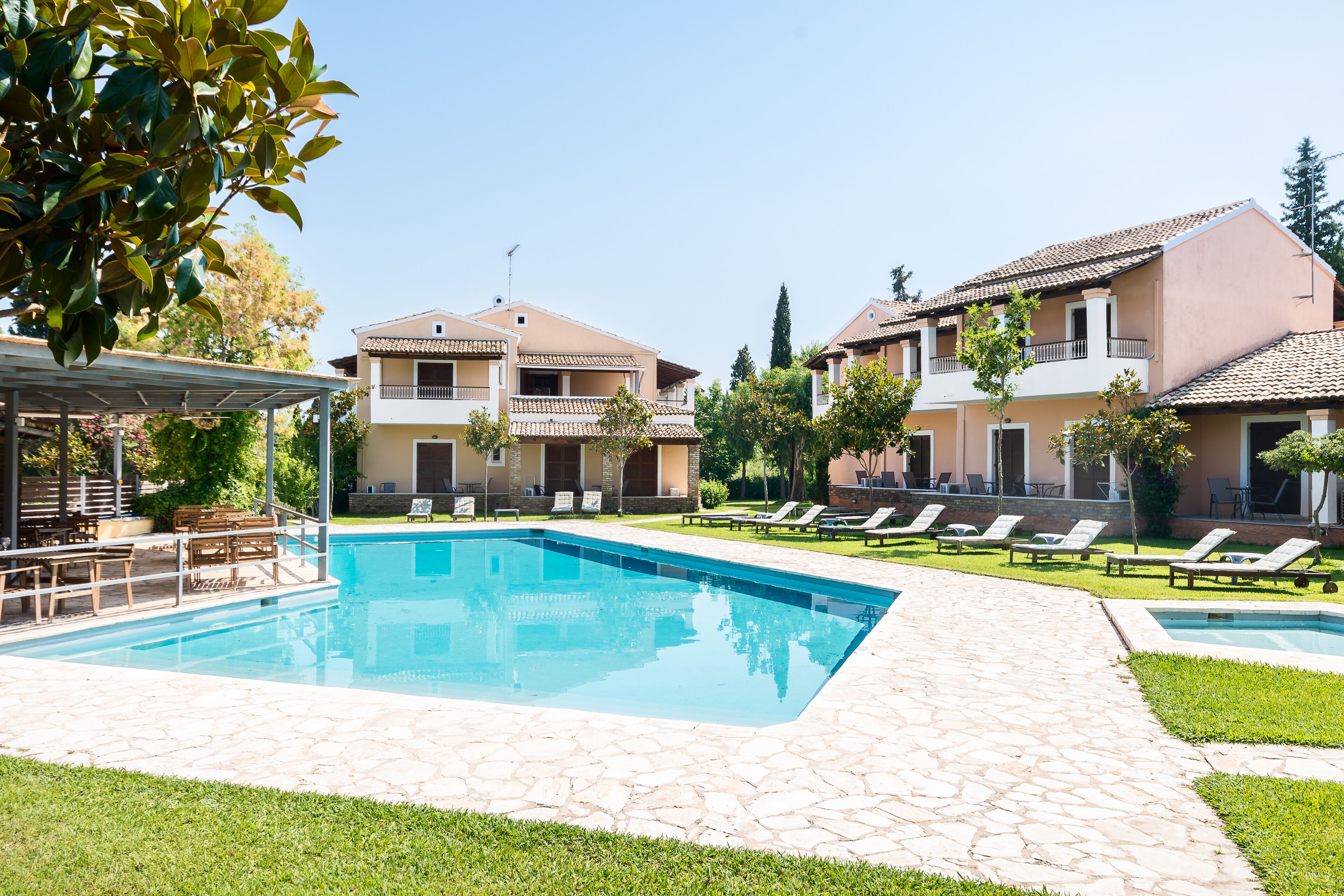A swimming pool area with lounge chairs and a covered seating area.
