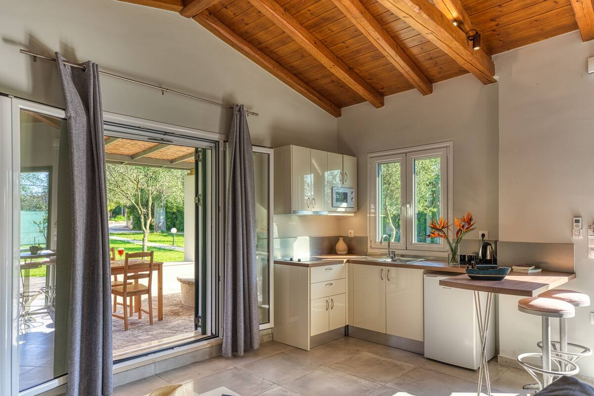 A modern kitchen with a wooden ceiling, sliding glass doors leading to a patio, and a built-in dishwasher.