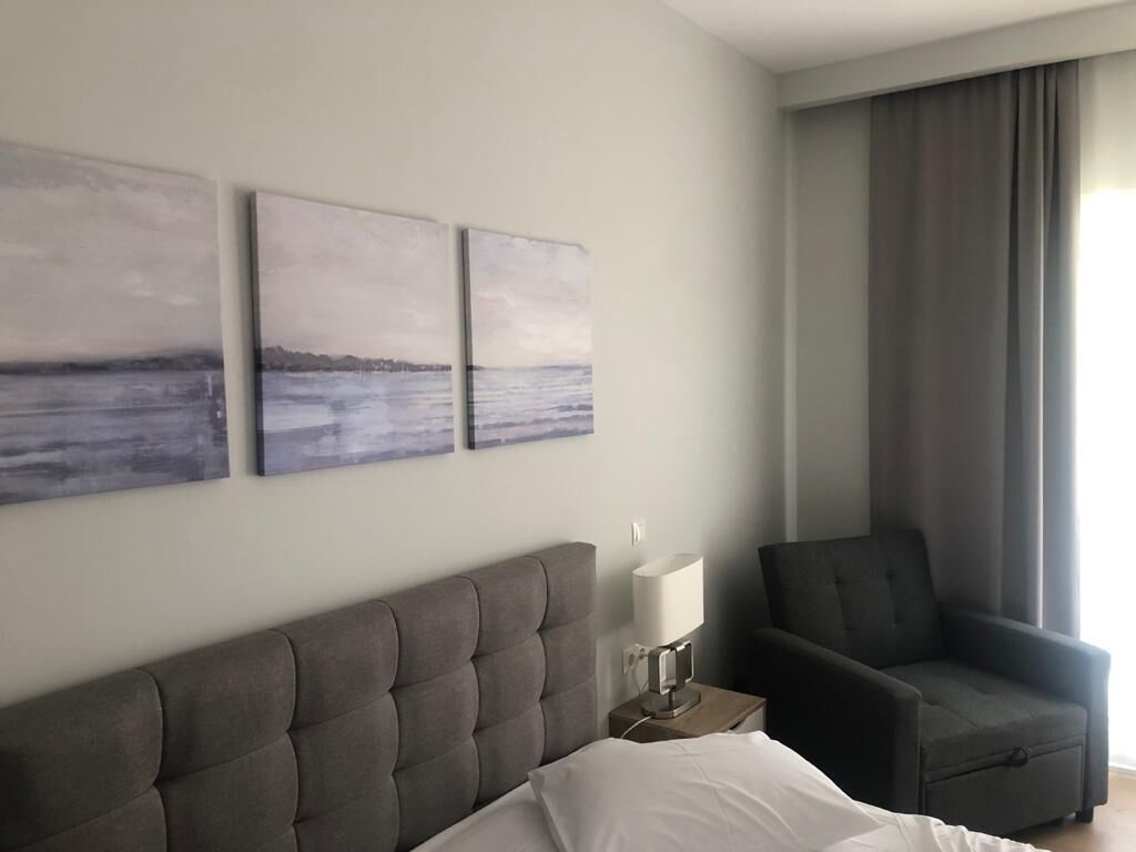 Una habitación de hotel con una cama, una silla y tres cuadros colgados en la pared.