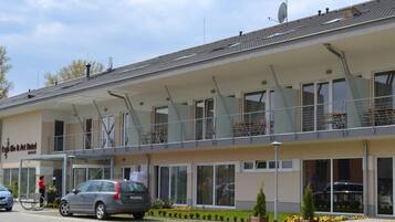 A two-story hotel with a covered outdoor seating area, large windows, and a sign reading "Hotel".
