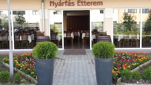 A restaurant named "Nyárfás Étterem" with outdoor seating visible through large windows.