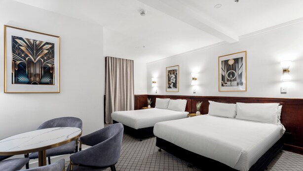 Une chambre d’hôtel avec deux lits, une table ronde et deux chaises.