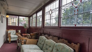 Une pièce dotée d’une grande fenêtre, d’un banc en bois et d’une chaise en osier.