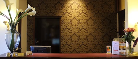 A reception desk with a dark wood finish, a ViewSonic monitor, and a floral arrangement with white flowers.