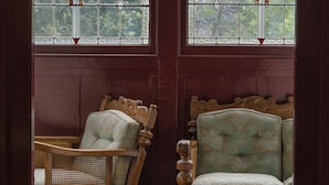 Le salon de Jessie est équipé de deux chaises en bois, d’un banc en bois et d’un sol recouvert d’une moquette rouge.