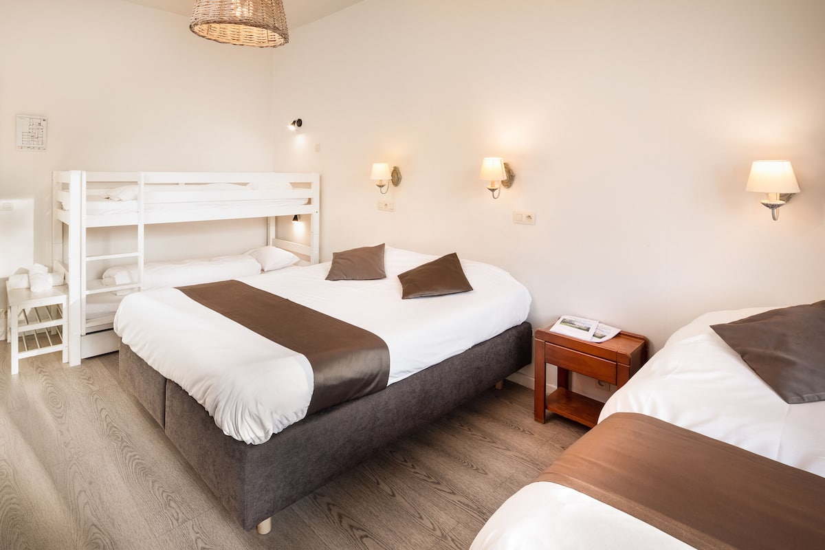 Ein Hotelzimmer mit Etagenbett, Nachttisch, Lampe und Holzboden.