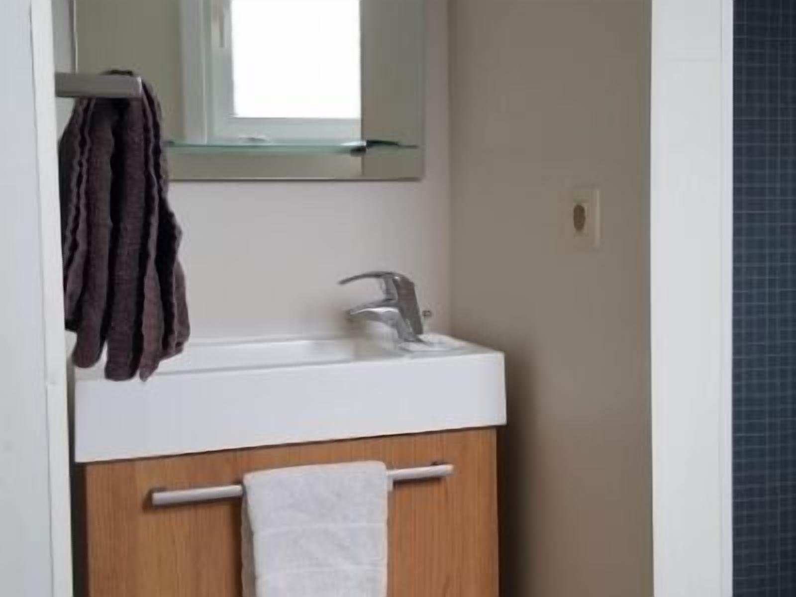 A bathroom with a white sink, a mirror, and a towel rack.