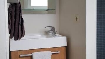 A bathroom with a white sink, a mirror, and a towel rack.