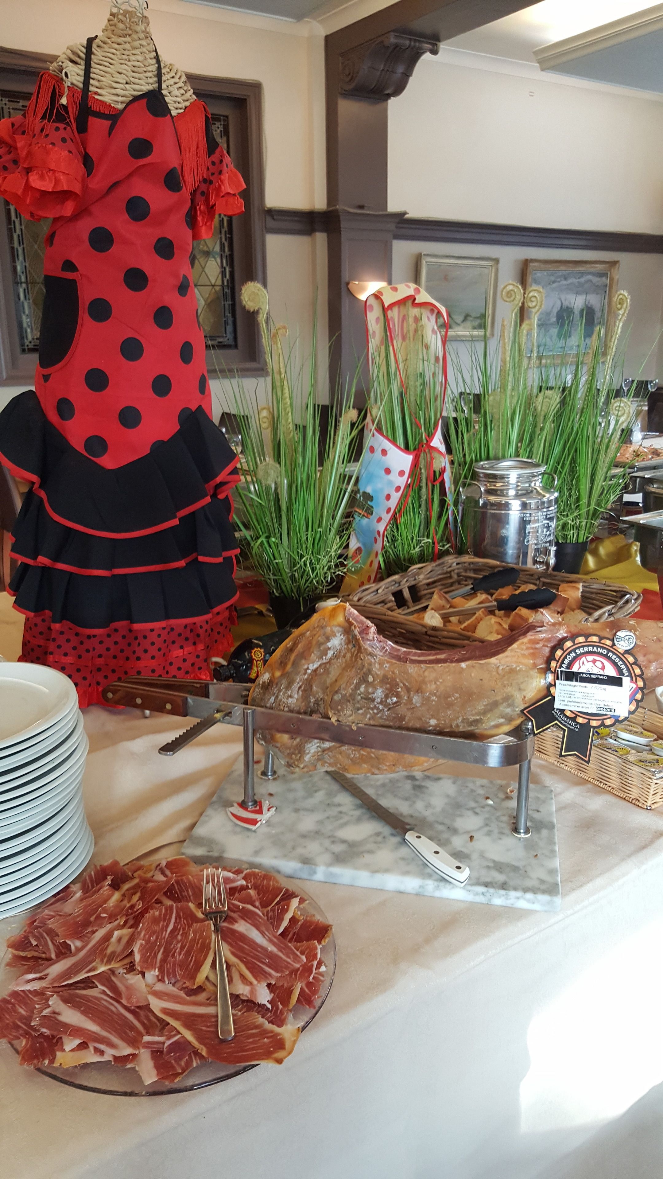 A buffet table with various food items, including sliced meats, bread, and decorative plants.
